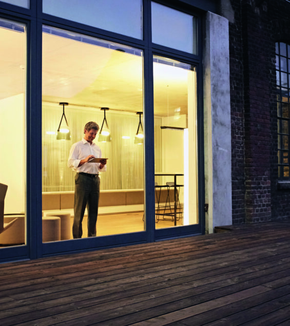 Germany, North-Rhine-Westphalia, Cologne, exterior view of man using tablet computer in modern building at night